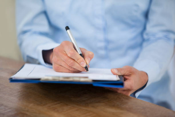 istock Mid section of doctor writing on clipboard 653819160