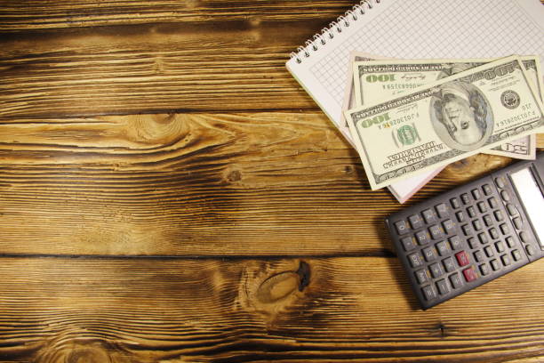 istock Notebook with dollars and calculator on wooden desk 653819264