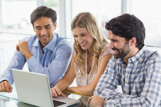 istock Smiling woman and two men using laptop 653822524