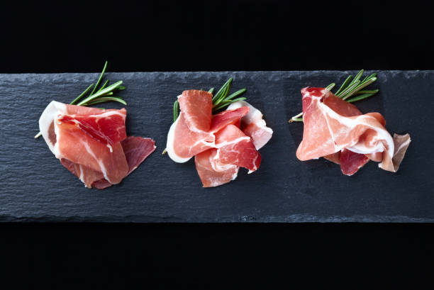 黒の背景にローズマリーの生ハム - prosciutto di parma ストックフォトと画像