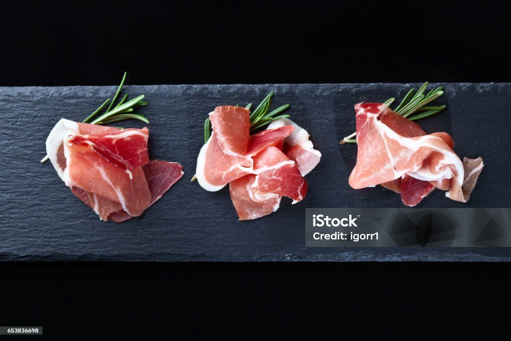 prosciutto with rosemary on a black background prosciutto with rosemary on a black background, top view Ham Stock Photo