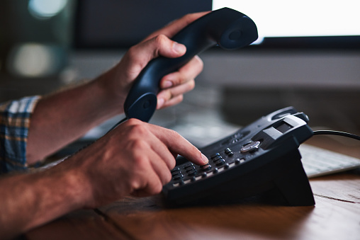 Shot of an unidentifiable businessman using a desk phone in the office