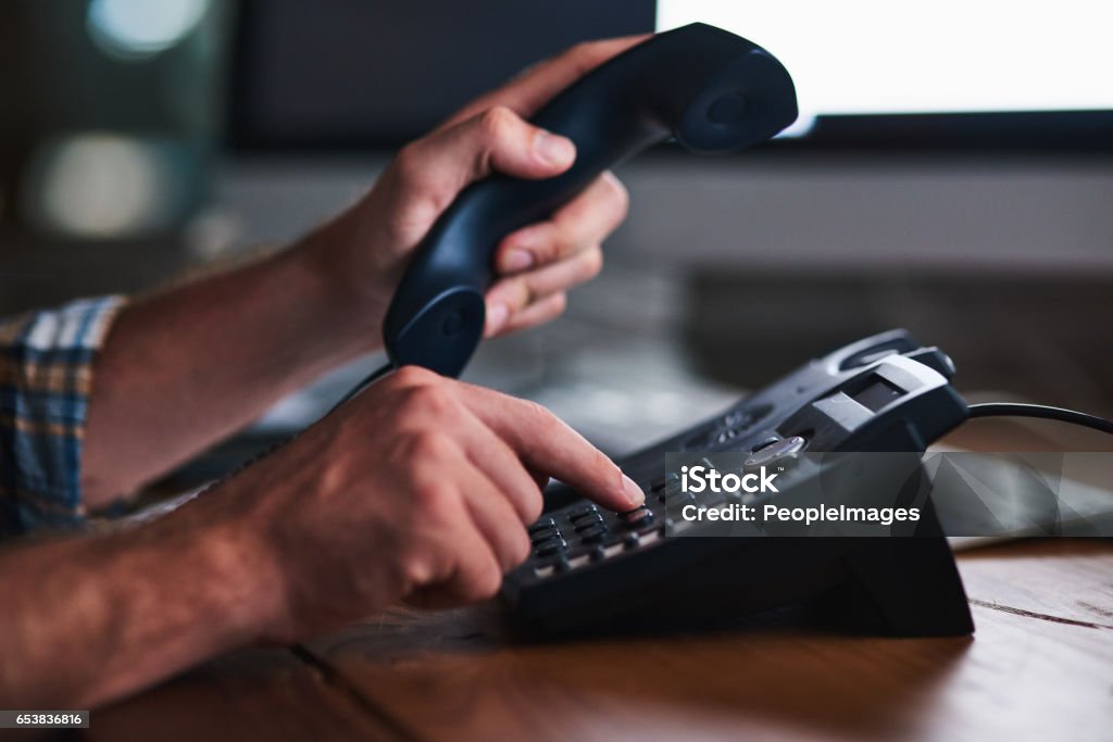 Keeping things old school Shot of an unidentifiable businessman using a desk phone in the office Rotary Phone Stock Photo