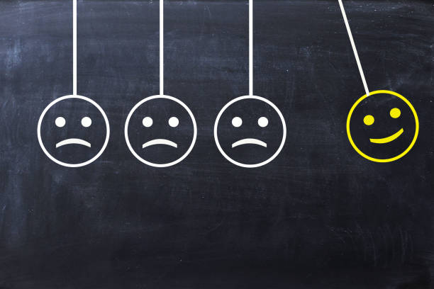 istock Spread happiness concept with happy and sad faces on newton’s cradle on blackboard 653837666