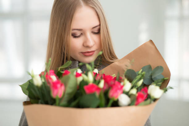 istock Woman looking at white and pink roses bouquet in studio 653840026