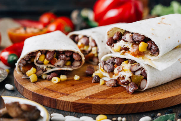 istock Nice vegetarian burrito over black table on wooden board. 653844596