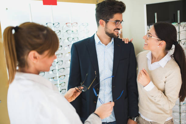 istock Smiling couple selecting eyeglasses in optical store 653845650