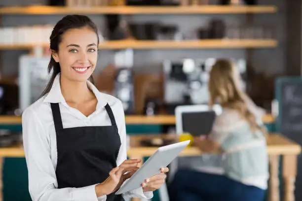 Portrait of smiling waitress using digital tablet in cafe