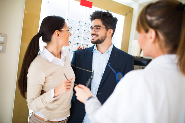 istock Smiling couple selecting eyeglasses in optical store 653849770