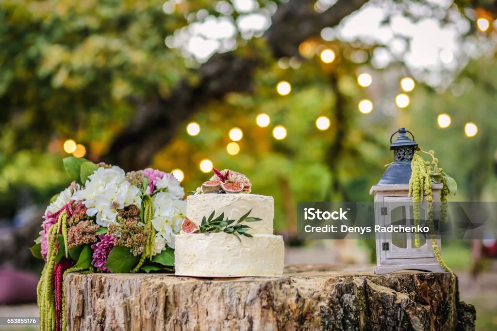 Beautiful wedding decoration with cake, bouquet of flowers and a lantern on a background of nature Beautiful wedding decoration with cake, bouquet of flowers and a lantern on background of nature Wedding Stock Photo