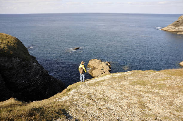 istock Man standing on edge of cliff overlooking sea. 653862350