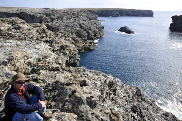 istock Man standing on edge of cliff overlooking sea. 653862844