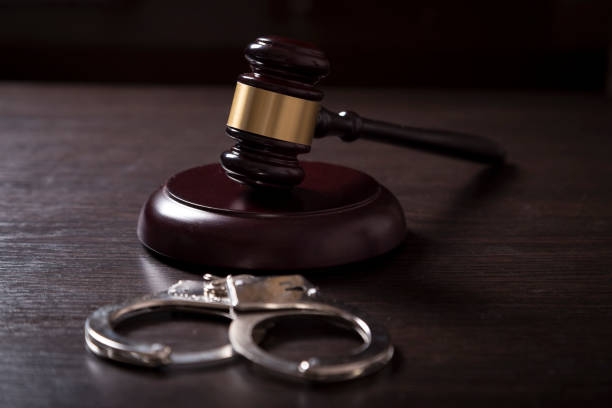 Under arrest Close up of a judge gavel and handcuffs in a courtroom. Selective focus cuff stock pictures, royalty-free photos & images