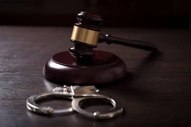 Close up of a judge gavel and handcuffs in a courtroom. Selective focus