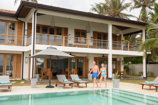 istock Senior couple walking by swimming pool holding hands 653867124