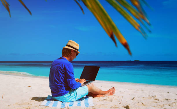 istock man with laptop on tropical beach 653867134