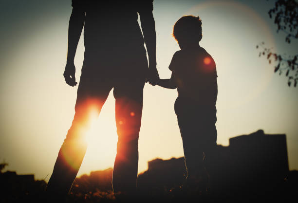 istock silhouette of father and son holding hands at sunset 653867178