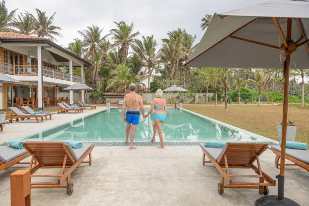istock Senior couple on poolside holding hands, rear view 653867188