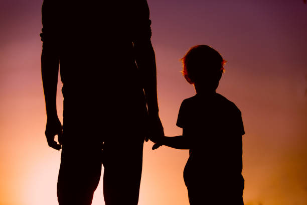 istock silhouette of father and son holding hands at sunset 653867248