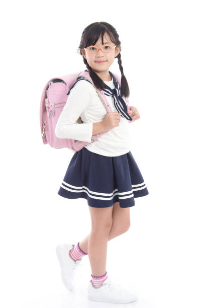 Asian child in school uniform with pink school bag on white background isolated