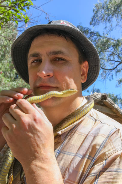 Man stands with snake tied like cravat on his neck