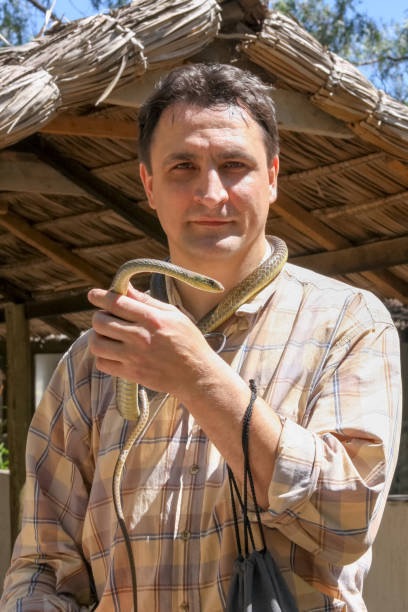 istock Man stands with snake tied like cravat on his neck 653868834
