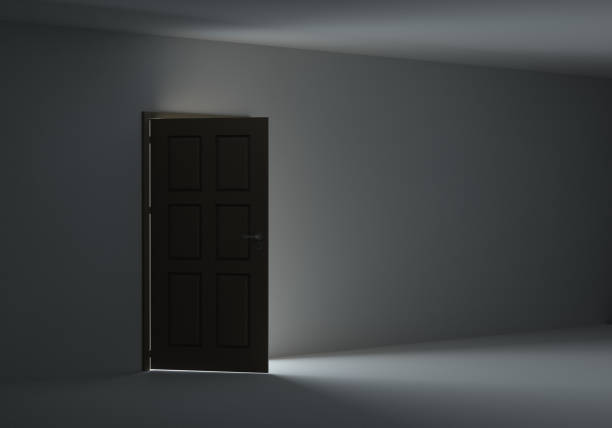 istock Open door with bright light streaming into very dark room 653869040