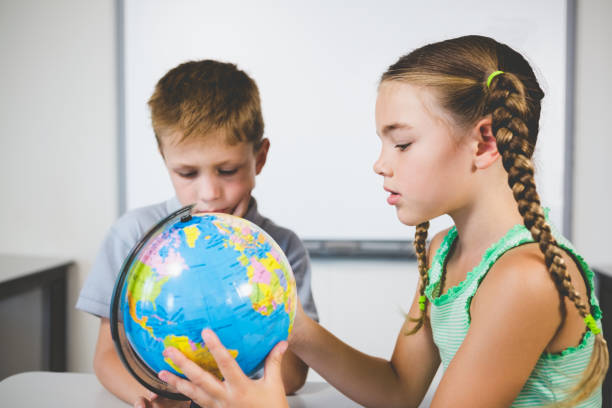 istock School kids looking at globe in classroom 653871450