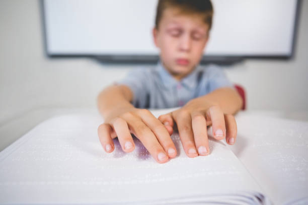 istock Schoolboy reading a braille book in classroom 653871806