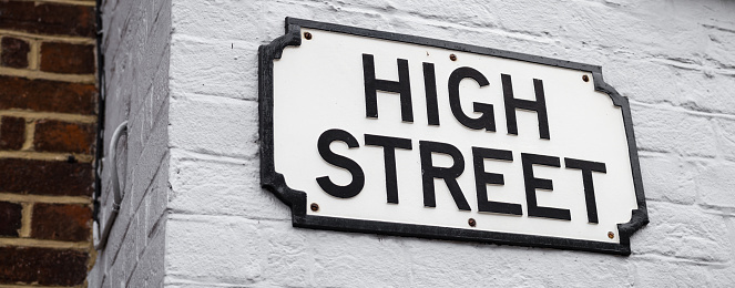 A simple British High Street sign on a painted brick wall.