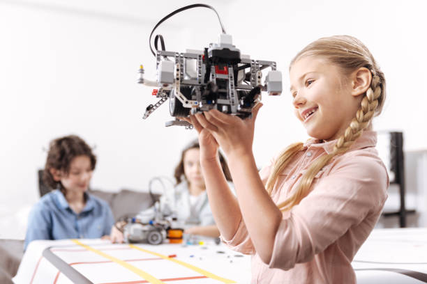istock Energetic little girl playing with robot at school 653875504
