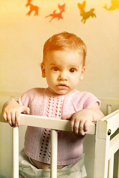 istock Baby girl standing in her bed 653876010