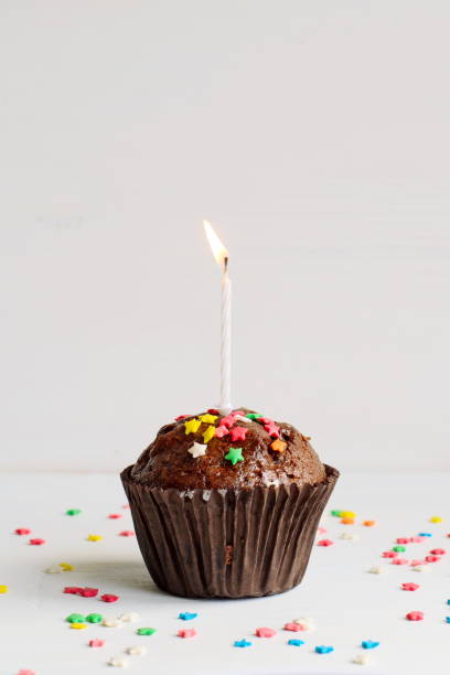 istock Birthday chocolate muffin with a small burning candle on white background 653876376