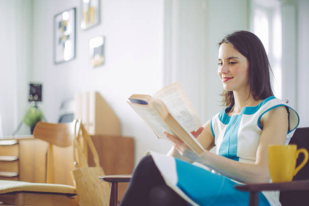 istock Young woman is reading a book at home 653876936