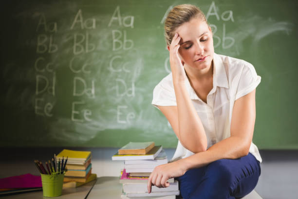 istock Tensed school teacher sitting in classroom 653878766