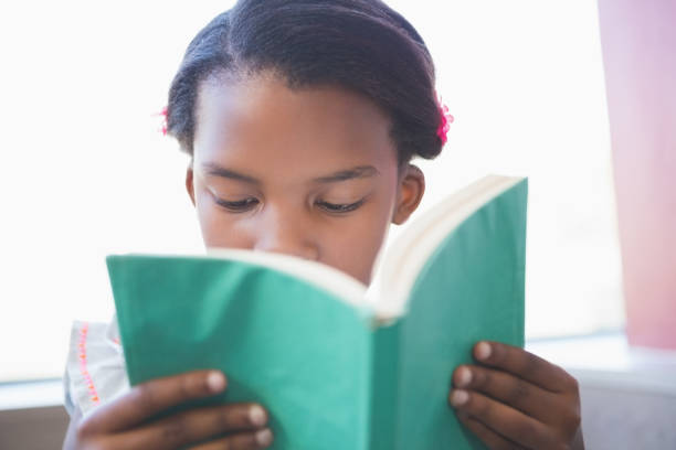istock Schoolgirl reading book in library 653879514