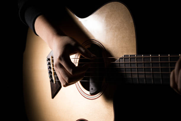 istock Woman playing guitar on black background 653879608