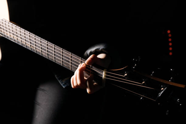 istock Woman playing guitar on black background 653879636
