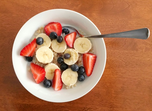 Overhead view of a bowl with steel cut oats, bananas,blueberries and strawberries