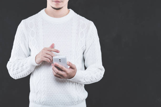 istock Young Japanese man wearing a white cable knit with a Smartphone 653882500