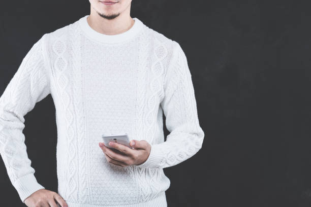 istock Young Japanese man wearing a white cable knit with a Smartphone 653882532