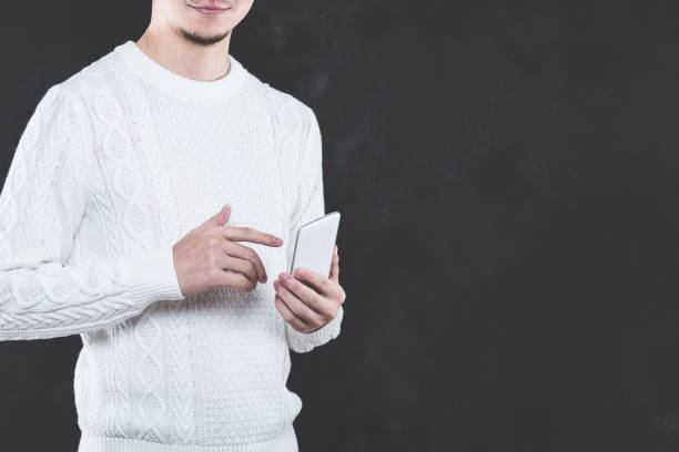 istock Young Japanese man wearing a white cable knit with a Smartphone 653882542