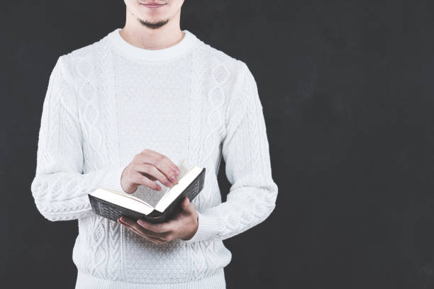 istock Young Japanese man wearing a white cable knit with a book 653882574