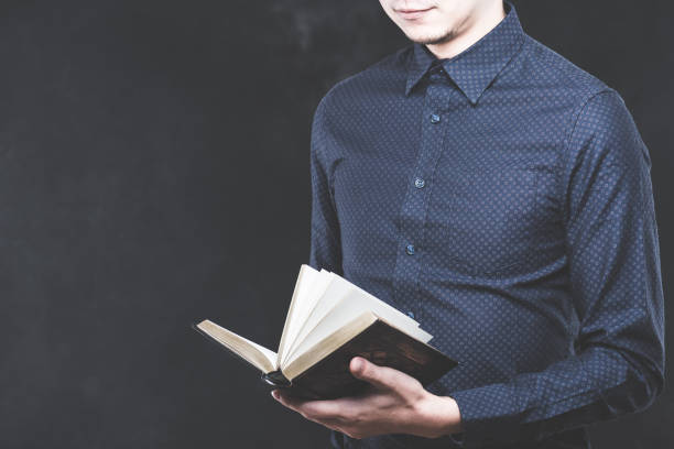 istock Young Japanese man wearing a black t-shirt with a book 653882884