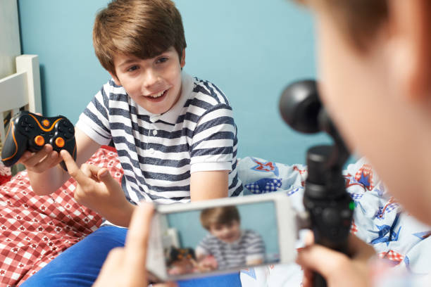 istock Two Boys Recording Gaming Blog In Bedroom 653897788