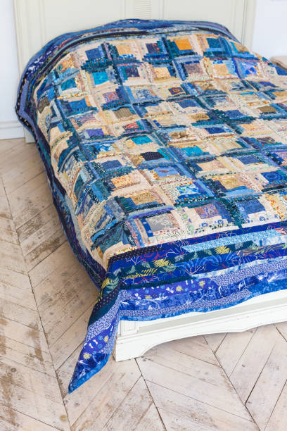 istock large bright double bed with a colored patchwork quilt in the white interior. blue scrappy blanket on the bed closeup 653897792