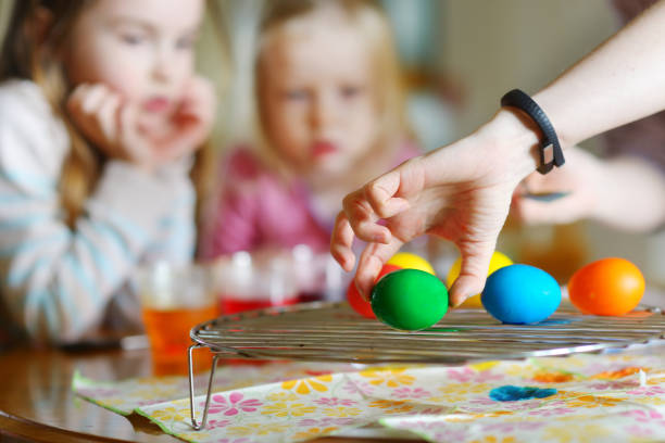 istock Young mother and her two daughters painting Easter eggs 653900346
