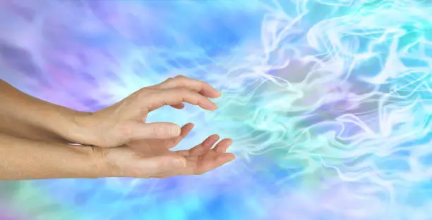 Female hands cupped sensing a gaseous field of ectoplasmic matter on a  blue background with copy space