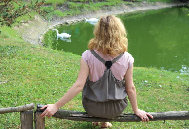 istock Woman on front of pond with swans. 653906970