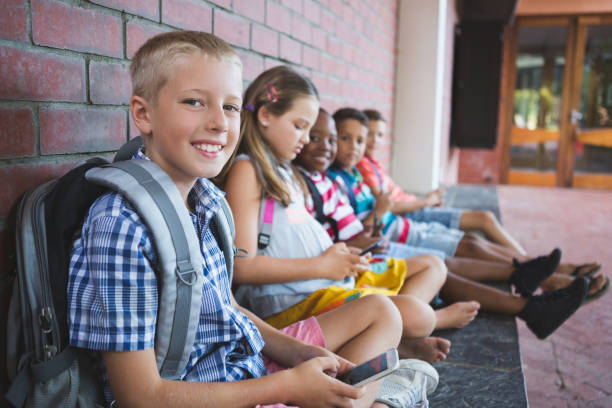 istock Schoolkids sitting in corridor and using mobile phone 653912178